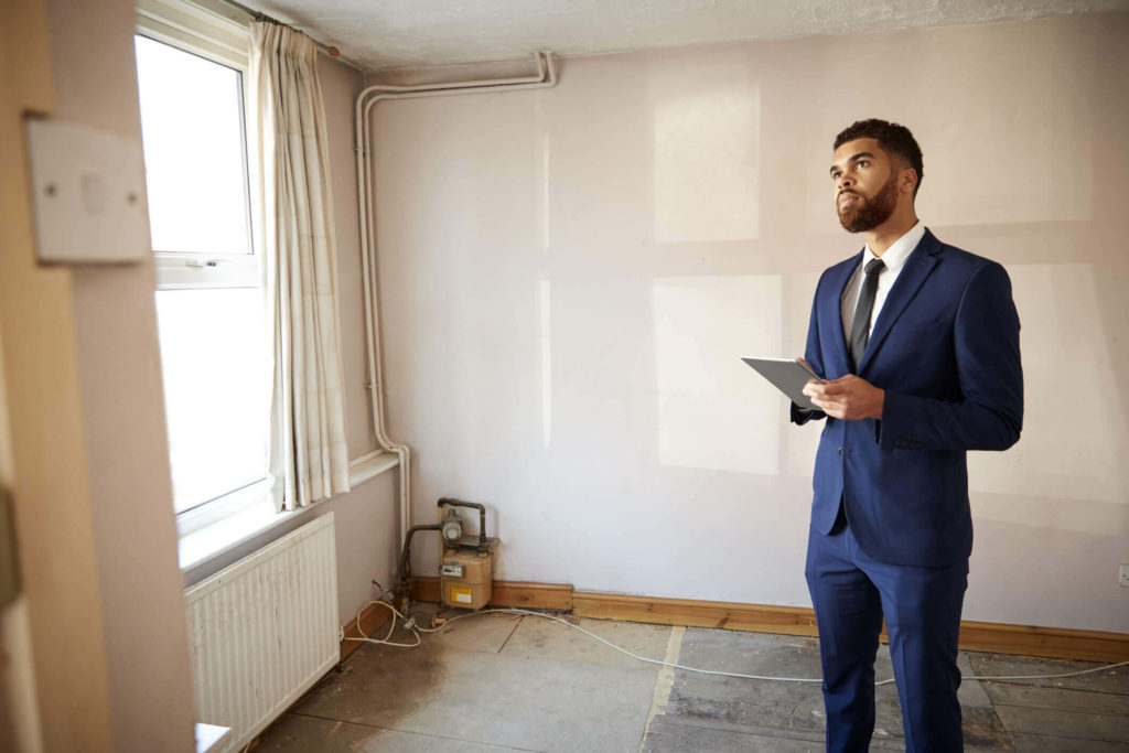 A imagem mostra um homem observando o ambiente interno de um apartamento. Foto para ilustrar o texto sobre vistoria de imóveis e desocupação